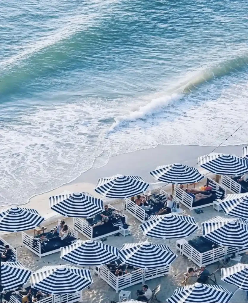 Blue and white striped umbrellas on beach next to water on Glenelg beach